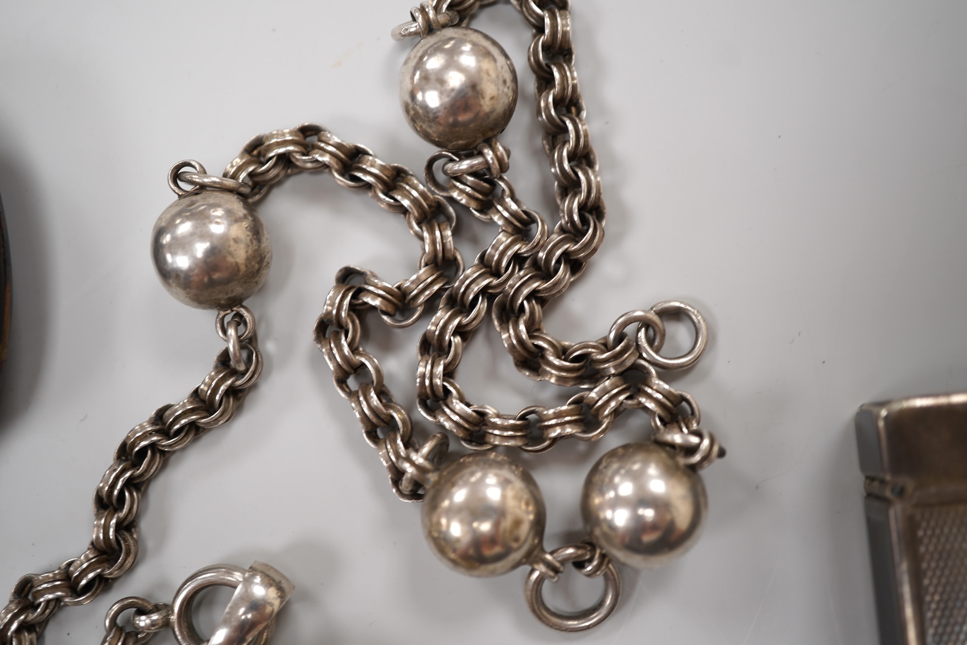 An early 20th century white metal oval locket, 40mm, on a silver chain, a silver plated Dunhill lighter, in Dunhill box, a white metal cased manual wind wrist watch and a tortoiseshell purse.